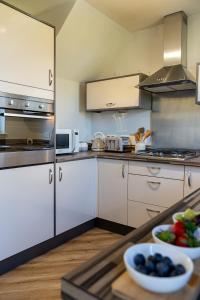a kitchen with white cabinets and a bowl of fruit at The Willows in Hurlet