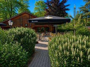 a building with an umbrella and a table and chairs at Boshuis de Boompjes in Doornspijk