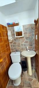 a bathroom with a white toilet and a sink at Contos de Alice Quartos in Tiradentes