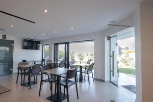 a dining room with tables and chairs and windows at Adele Hotel Ksamil in Ksamil