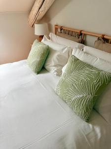 a white bed with two green pillows on it at La Loggia dei Mercanti in Cuneo