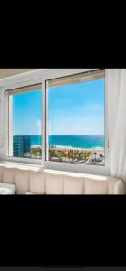 a view of the ocean from a window with a couch at דירה על הים in Ashdod
