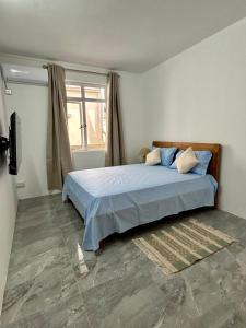 a bedroom with a bed with blue sheets and a window at Serenity villa in Pointe aux Biches