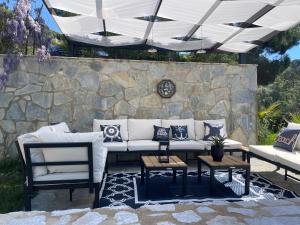 a patio with a white couch and chairs and a stone wall at Damari Luxury 3 Bedroom Villas with Private Pool, Skiathos in Skiathos