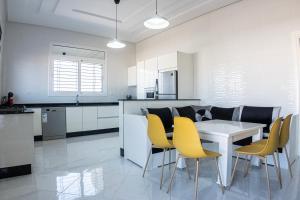 a kitchen with a white table and yellow chairs at Villa Raha in Selouane +31 photos