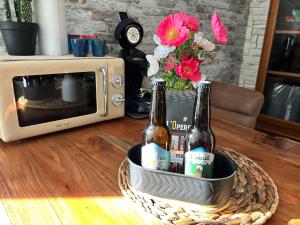 two bottles of beer in a basket in front of a microwave at Cocon romantique Jardin de la princesse idéal couple Calme & nature Vosges in Senones