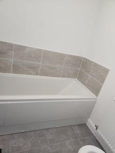 a bathroom with a white tub and a toilet at Edinburgh Road Nuneaton in Moffat