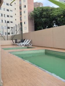 a swimming pool with two chairs and a table at APTO 42M l 7 km Alphaville in Osasco