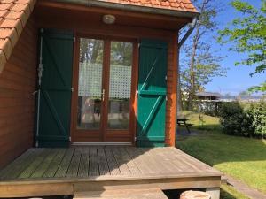 a small house with green doors and a wooden porch at Chalet confortable à Berck-sur-Mer in Berck-sur-Mer