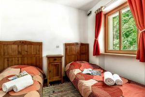 two beds in a room with red curtains at House By The Stream in Soča Valley - Happy Rentals in Avče
