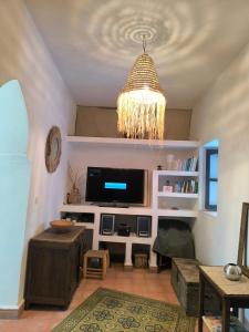 a living room with a television and a chandelier at Riad Louisa in Chefchaouen