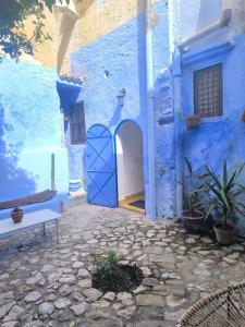 a blue building with a blue door in a courtyard at Riad Louisa in Chefchaouen