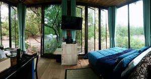 a bedroom with a blue bed in a room with windows at Calm at Bangphat in Ban Khiam