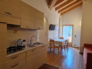 a kitchen with wooden cabinets and a table with chairs at Appartamento da Meto in San Martino di Castrozza
