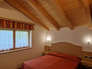 a bedroom with a red bed and a window at Appartamento da Meto in San Martino di Castrozza