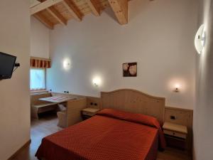 a bedroom with a bed and a desk and a television at Appartamento da Meto in San Martino di Castrozza