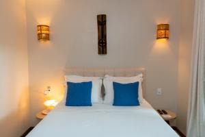 a bedroom with a bed with blue pillows and two lights at Villa Zen Hotel in Camocim +87 photos