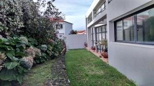 een tuin naast een wit huis met een hek bij Surf & Guest Lorena´s House in Ribeira Grande