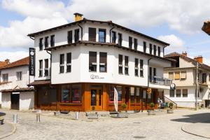 a large white building with black windows on a street at Kulla e Sahatit - Boutique Hotel in Old Bazaar in Gjakove
