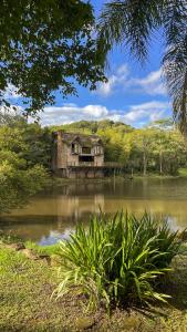 an old house sitting in the middle of a pond at Sítio Mello in Igrejinha
