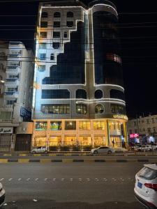 a tall building at night with cars parked in front of it at Royal Family Hotel in ‘Aţţān