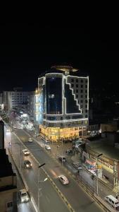a lit up building on a city street at night at Royal Family Hotel in ‘Aţţān