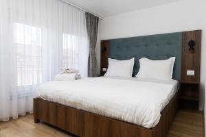 a bedroom with a large bed with white sheets at Kulla e Sahatit - Boutique Hotel in Old Bazaar in Gjakove