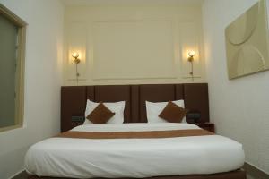 a bedroom with a large bed with white sheets and pillows at Divine Hotel in Karnal