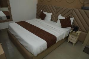 a bedroom with a large bed with white sheets and brown pillows at Divine Hotel in Karnal
