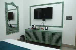 a bedroom with a television on a dresser with a mirror at Divine Hotel in Karnal
