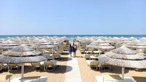 a group of umbrellas and chairs on a beach at B&B Colori del Salento in Presicce