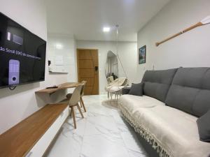 a living room with a couch and a flat screen tv at Atlântico 33 Guilhermina in Praia Grande