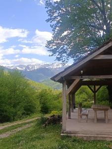 a picnic shelter with a bench and mountains in the background at Anika apartmani in Tjentište +12 photos