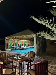a tent with a table and chairs in front of a stage at Gite d étape Khettara Oasis in Er Rachidia