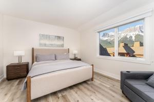a bedroom with a bed and a window and a couch at Spectacular Penthouse With Amazing Views, Indoor Pool and Hot tub in Canmore +65 photos