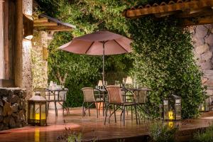 eine Terrasse mit Tischen, Stühlen und einem Sonnenschirm in der Unterkunft Lares De Chacras in Chacras de Coria