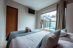 a bedroom with a large bed with a large window at Casa em Jacumã com Piscina, 5 Suítes e Fliperama in Conde