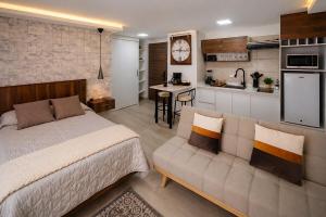 a bedroom with a bed and a couch and a kitchen at CarDiem Suites in Baños