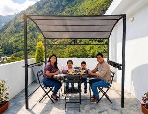 a family sitting at a table on a balcony at CarDiem Suites in Baños