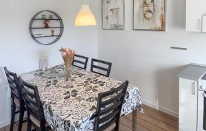 a dining room table with chairs and a vase of flowers on it at Stunning Home In Ringkøbing With Wifi in Ringkøbing