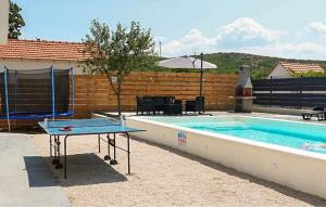 a ping pong table next to a swimming pool at Amazing Home In Dugobabe in Dugobabe