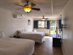 a bedroom with two beds and a ceiling fan at Sara Placid Inn & Suites in Saranac Lake