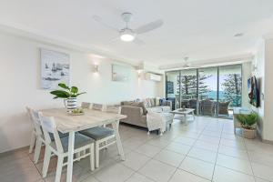 a dining room and living room with a table and chairs at Dwell @ 22, Oceanfront Apartment in Bargara