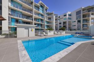 a swimming pool in front of a apartment building at Dwell @ 22, Oceanfront Apartment in Bargara