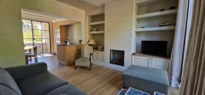 a living room with a couch and a tv at Authentiek Vakantiehuis Bos-en-Veld - Prive-tuin - Fietsvriendelijk vlakbij Brugge in Wingene