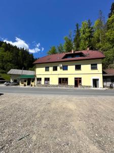 a large yellow building on the side of a road at Rina Apartments, Cozy Riverside Stay in Luče, near Logar Valley in Luče