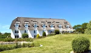 a large white building with a gray roof at Alago Hotel am See in Cambs