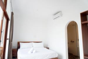 a bedroom with a bed with white sheets at Home Riki in Badung