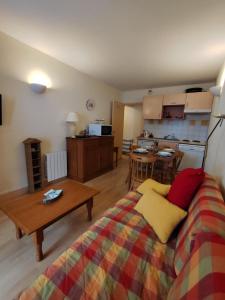 a living room with a bed and a kitchen at Le Carré Coloré in Ustou