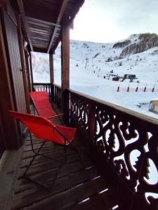 a red chair sitting on a balcony with a snow covered slope at Le Carré Coloré in Ustou